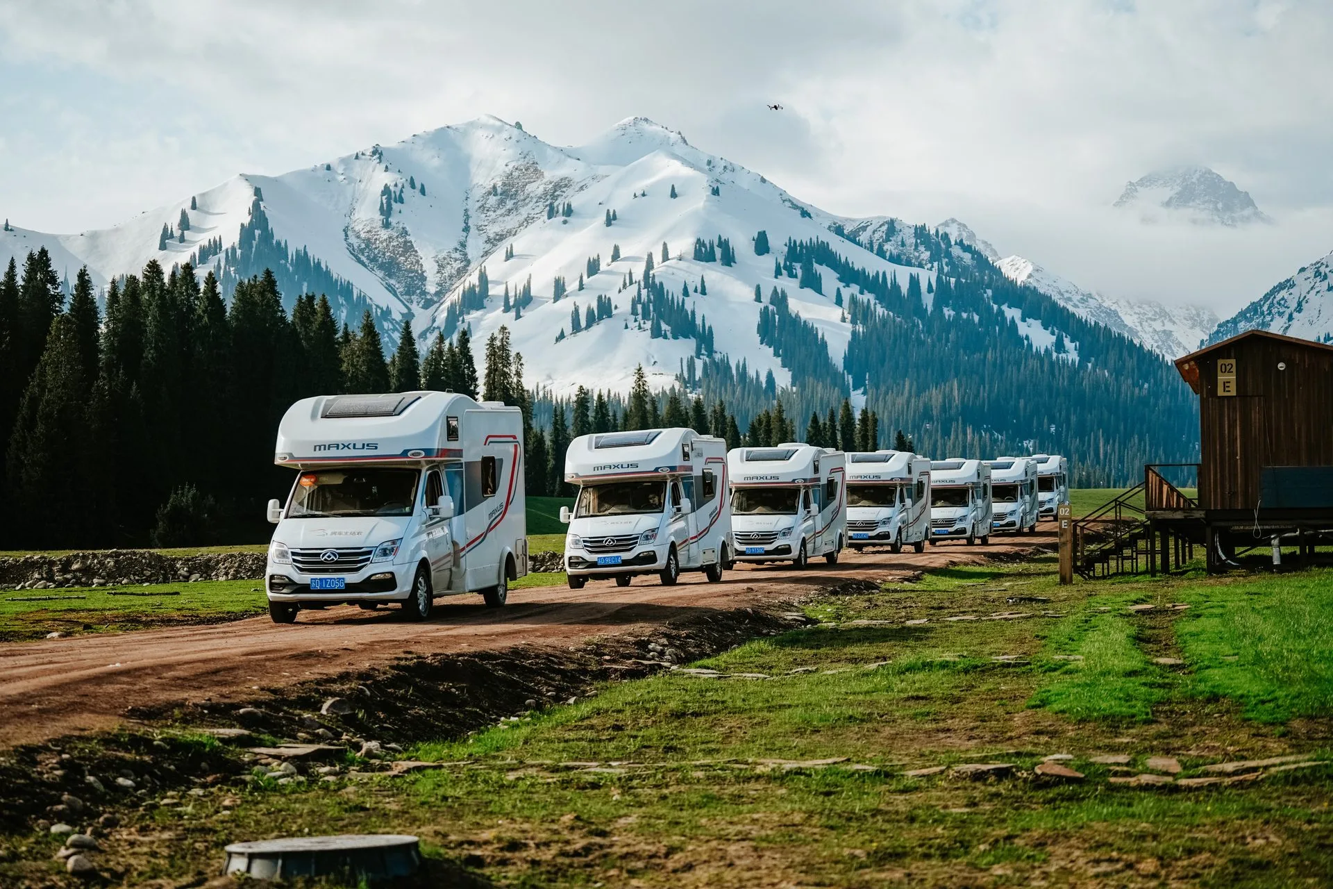 RV2GO fleet of SAIC Maxus campervans lined up against snow-capped mountains in Xinjiang, China